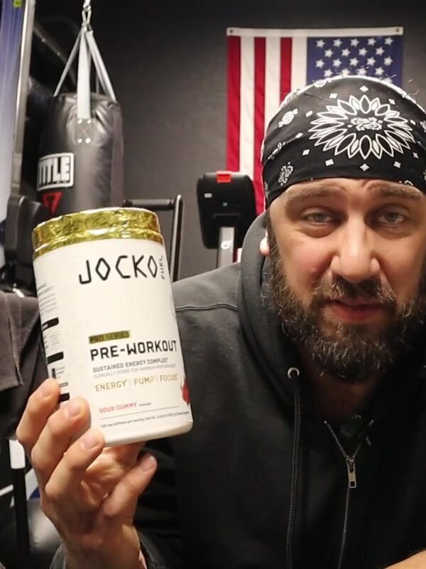 Big Mike holding Jocko Fuel Pro Series pre-workout in his home gym